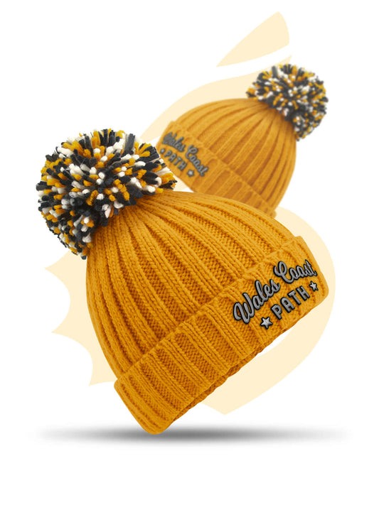 Embroidered mustard yellow Wales Coast Path chunky knitted beanie with cuffed design and multi-coloured pom pom.